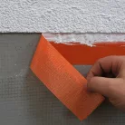 Blue Dolphin outdoor plaster masking tape applied to a rough wall surface before plastering – strong adhesion and reliable masking